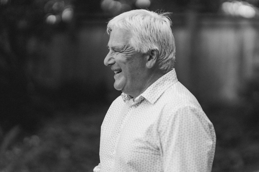 Black and white portrait of joyful man in light shirt smiling during outdoor celebration.