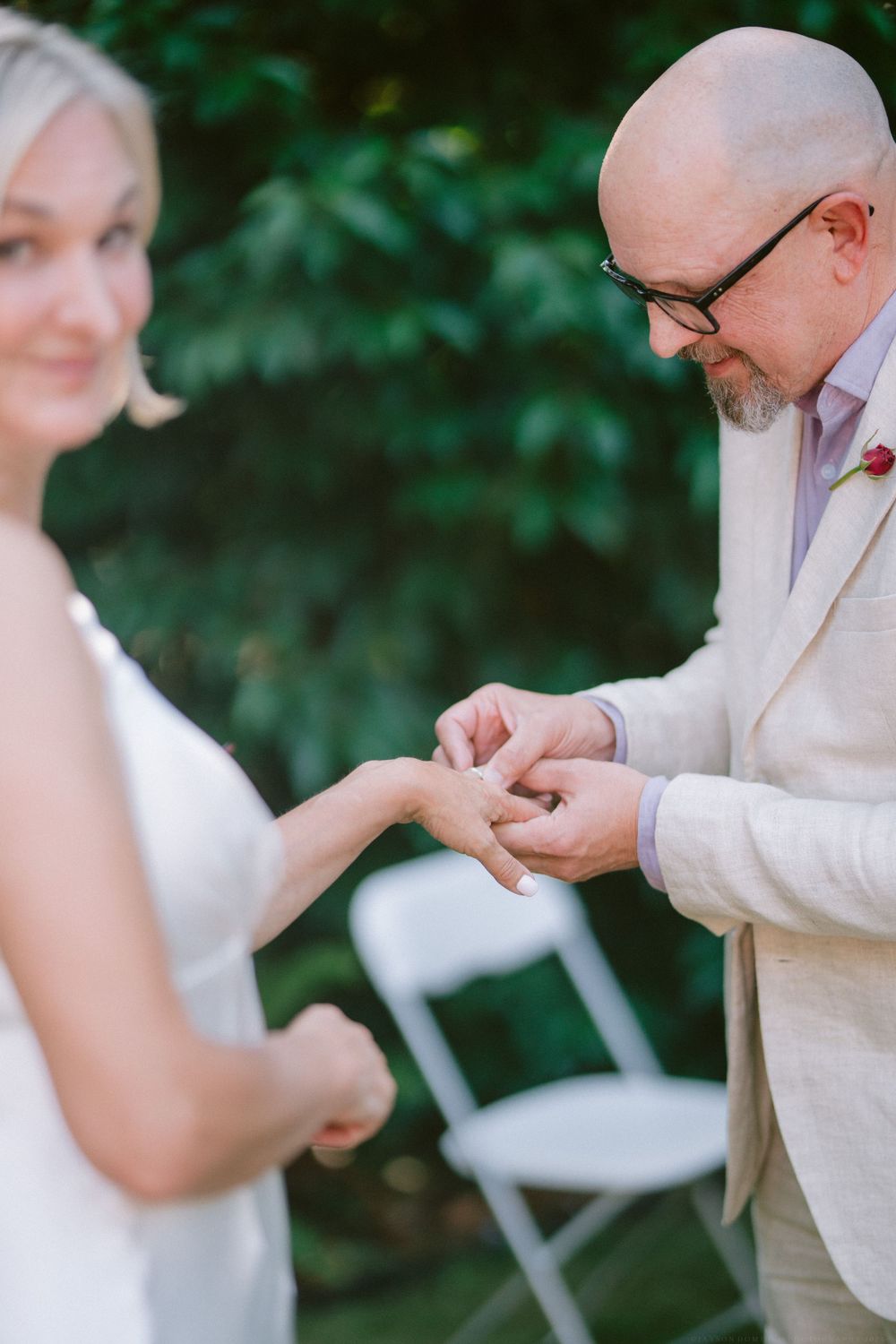 Close-up of ring exchange during intimate outdoor wedding ceremony.