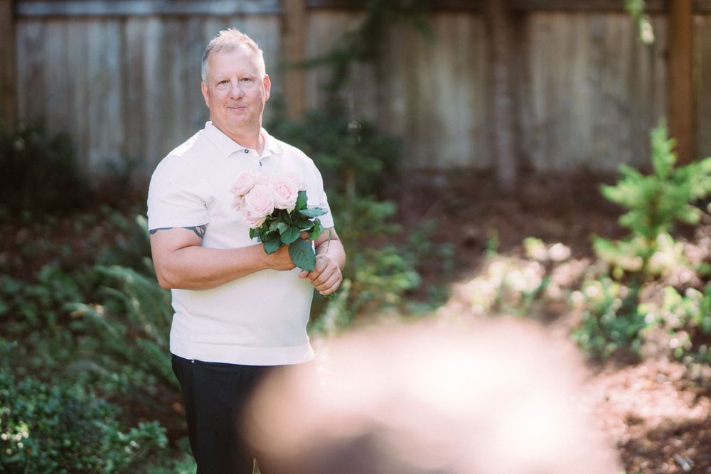 Person holding floral bouquet in sunlit garden setting.