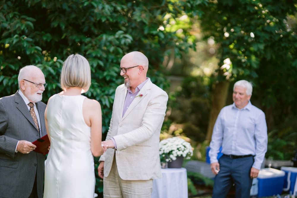 Intimate backyard wedding ceremony with officiant and guests in attendance.
