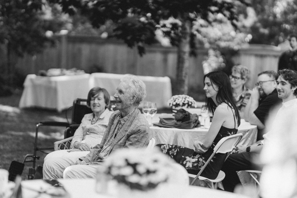 Black and white photo of guests gathered at outdoor reception with tables and refreshments.