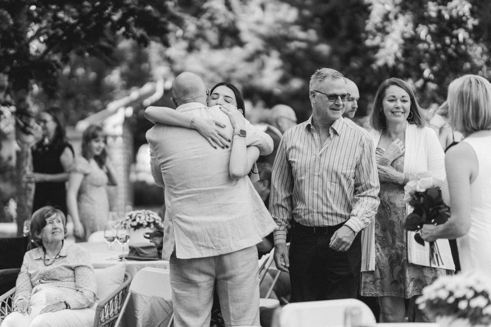 Black and white photo of guests embracing at an outdoor celebration.