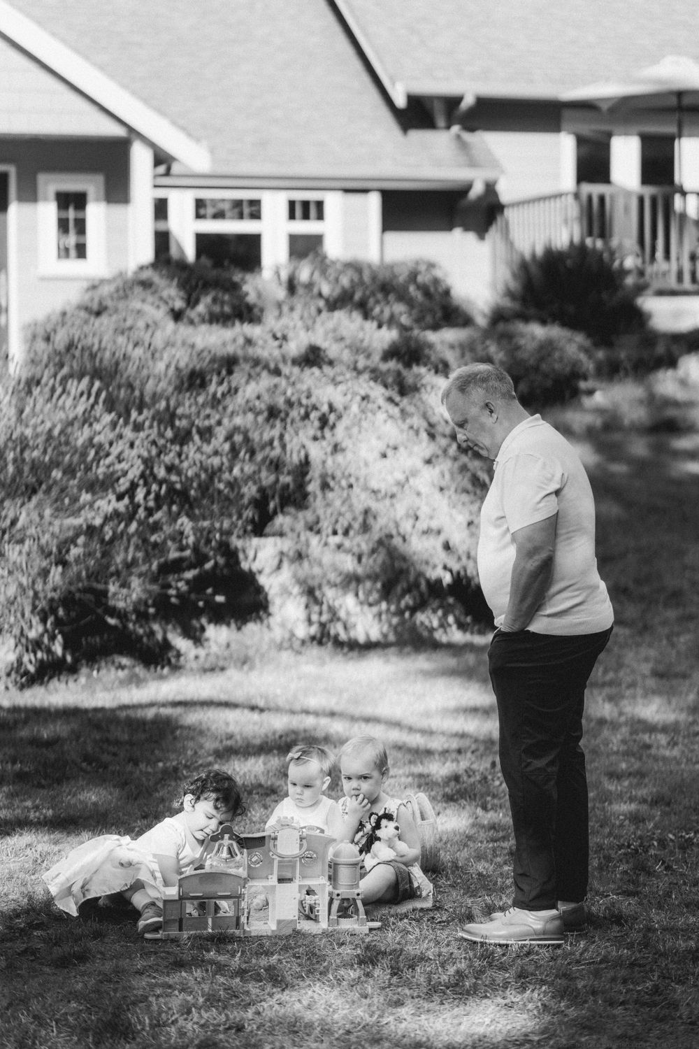 Black and white photo of children playing with blocks in a residential backyard.