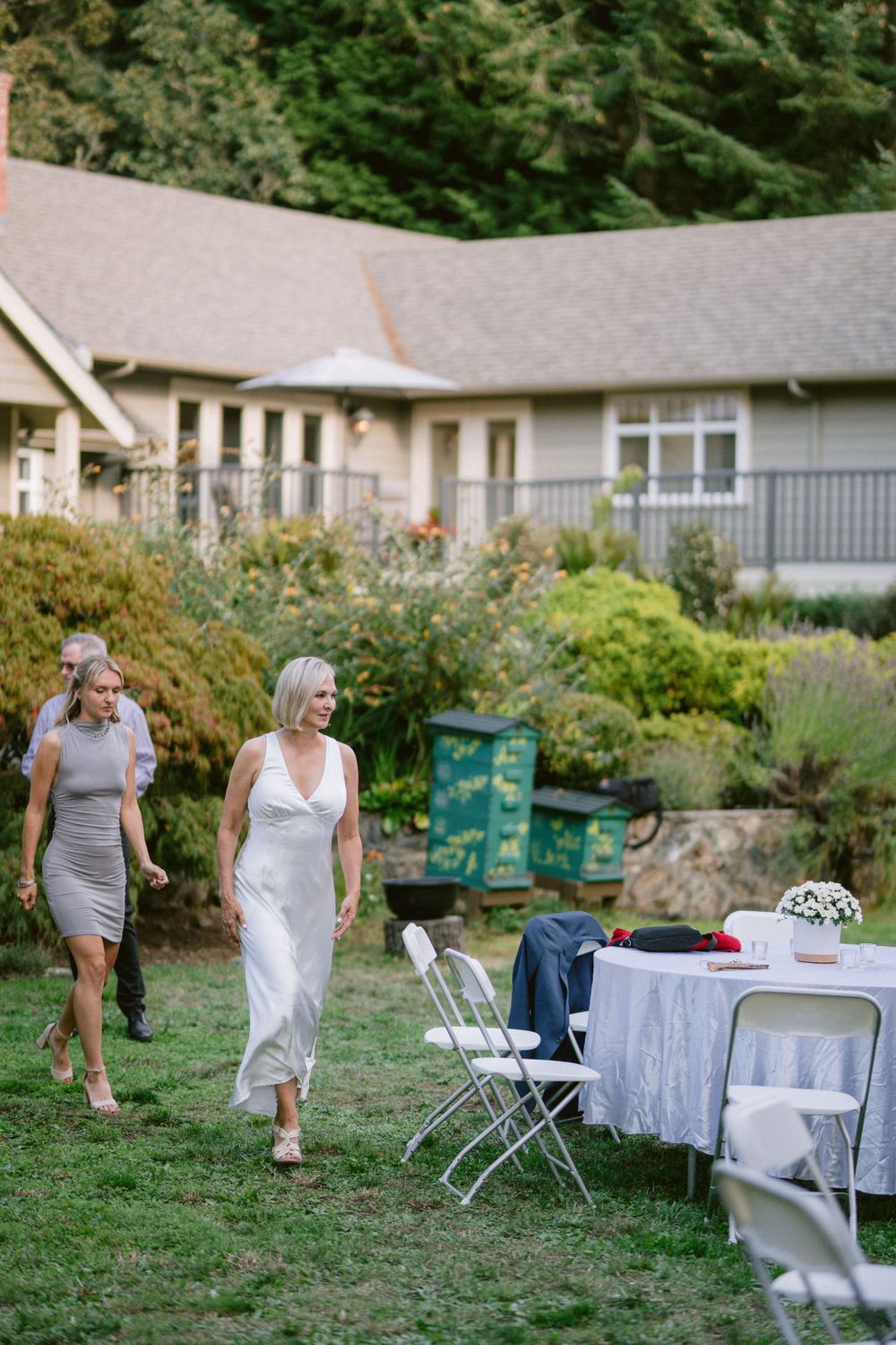 Women walking through a garden party setting with tables and chairs.