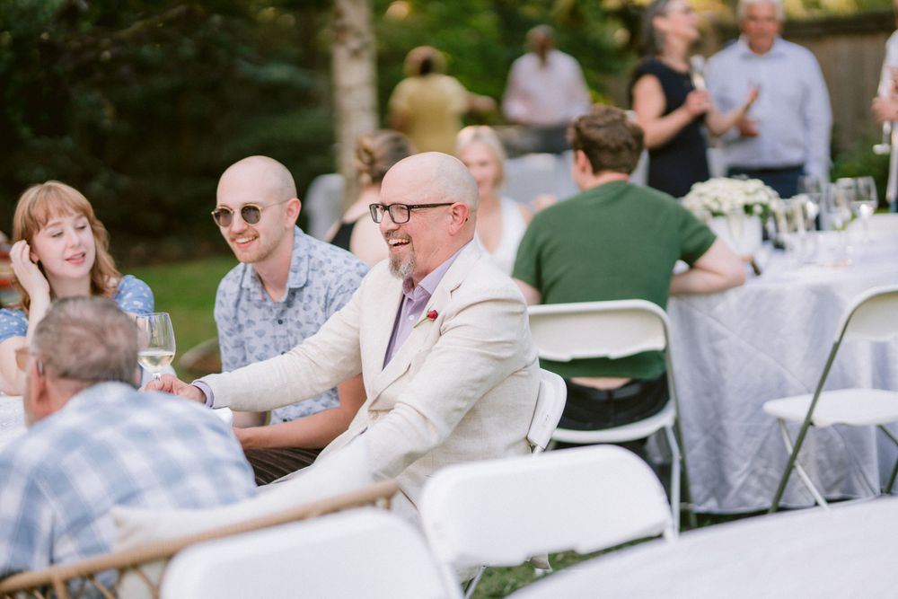 Guests enjoying conversation at outdoor tables during a summer celebration.