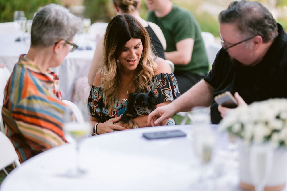 Guests enjoying conversation and laughter around a table at an outdoor event.