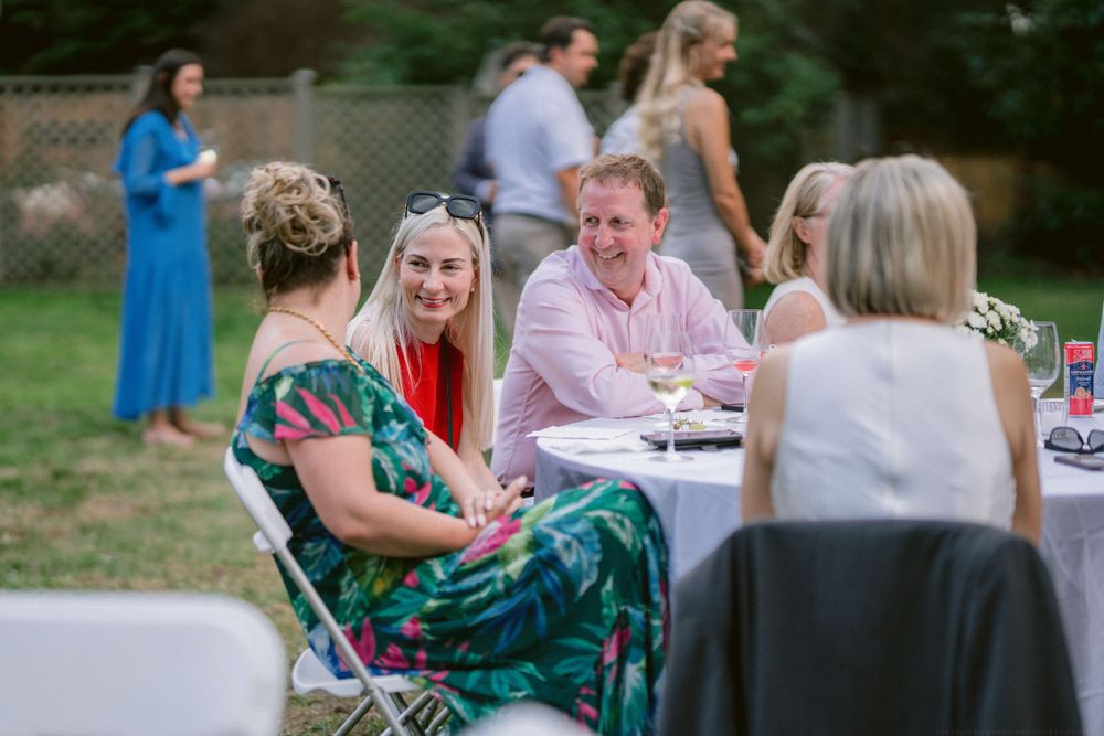 Group of guests chatting and socializing at outdoor tables during a summer event.