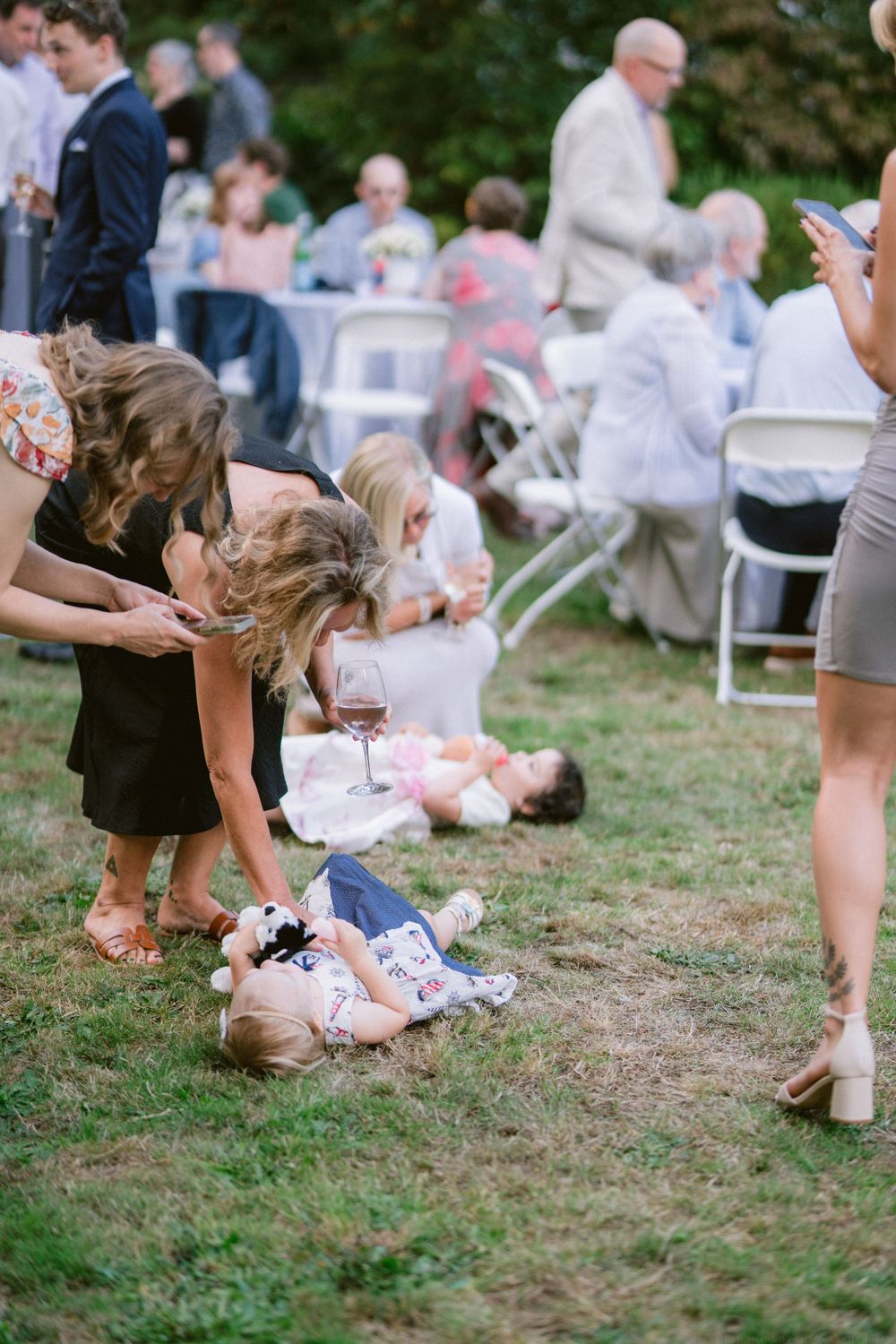 Candid moment of guests interacting during an outdoor party with folding chairs.