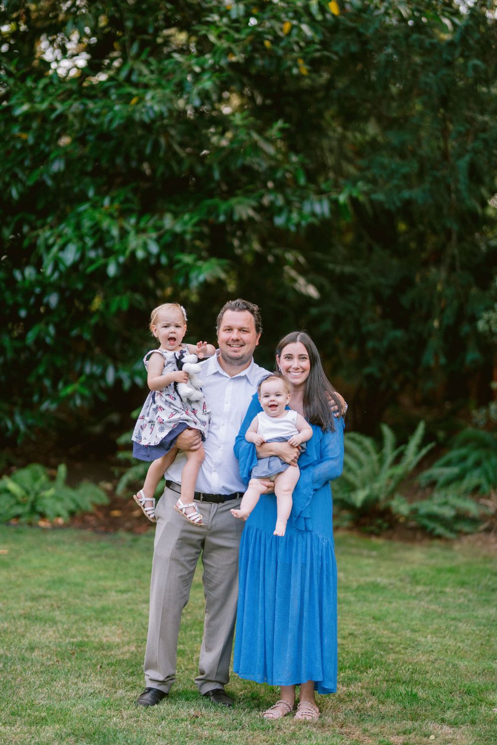 Family portrait taken on grass with green trees in background.