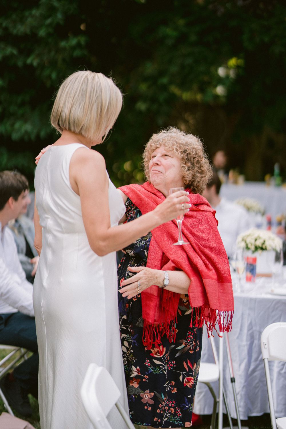 Two people share a warm embrace at an outdoor wedding reception.