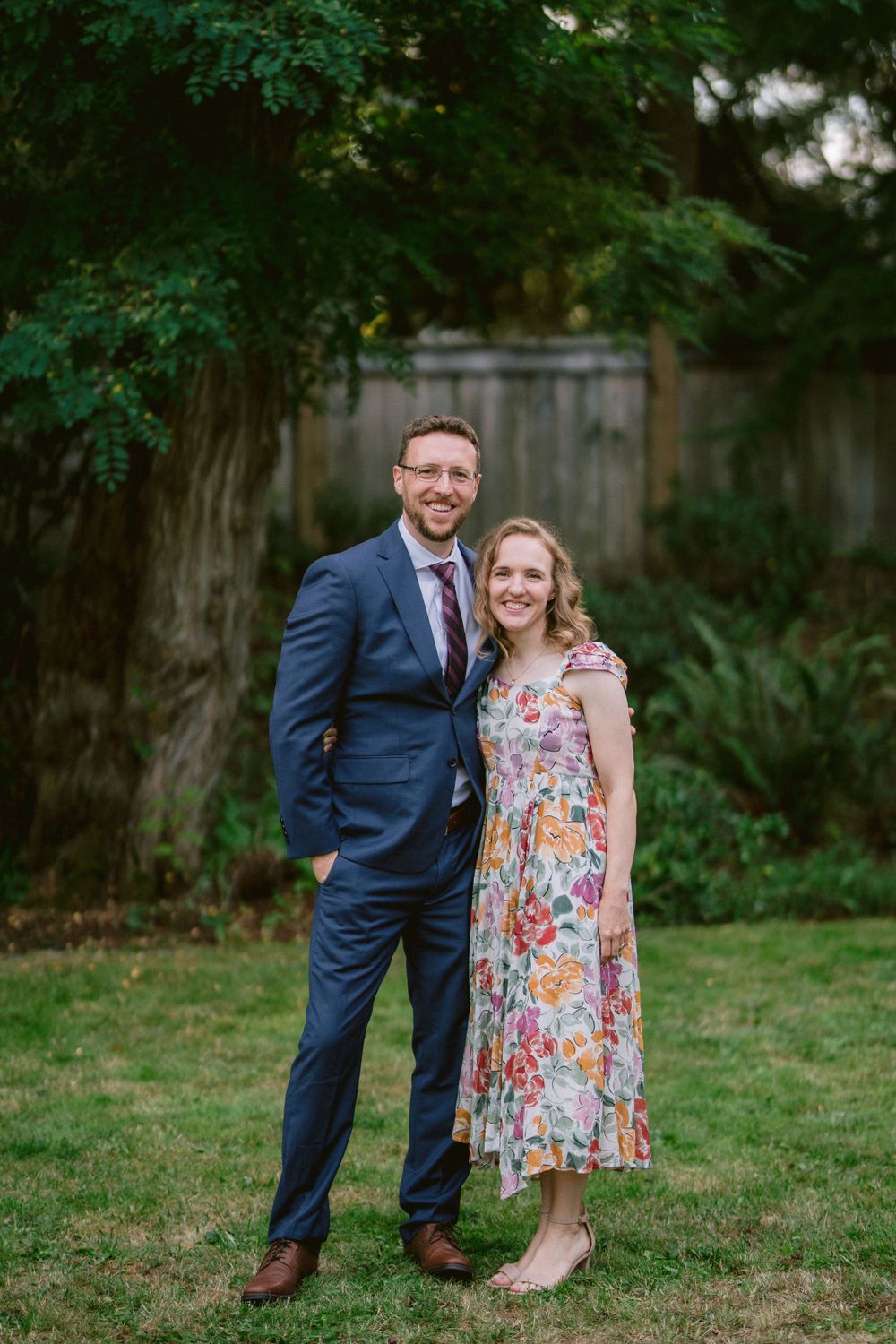 A couple poses for a portrait in a backyard garden setting.