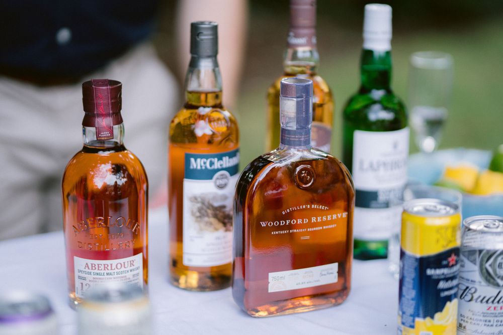 Close-up shot of whiskey bottles and beverages arranged on a bar table.