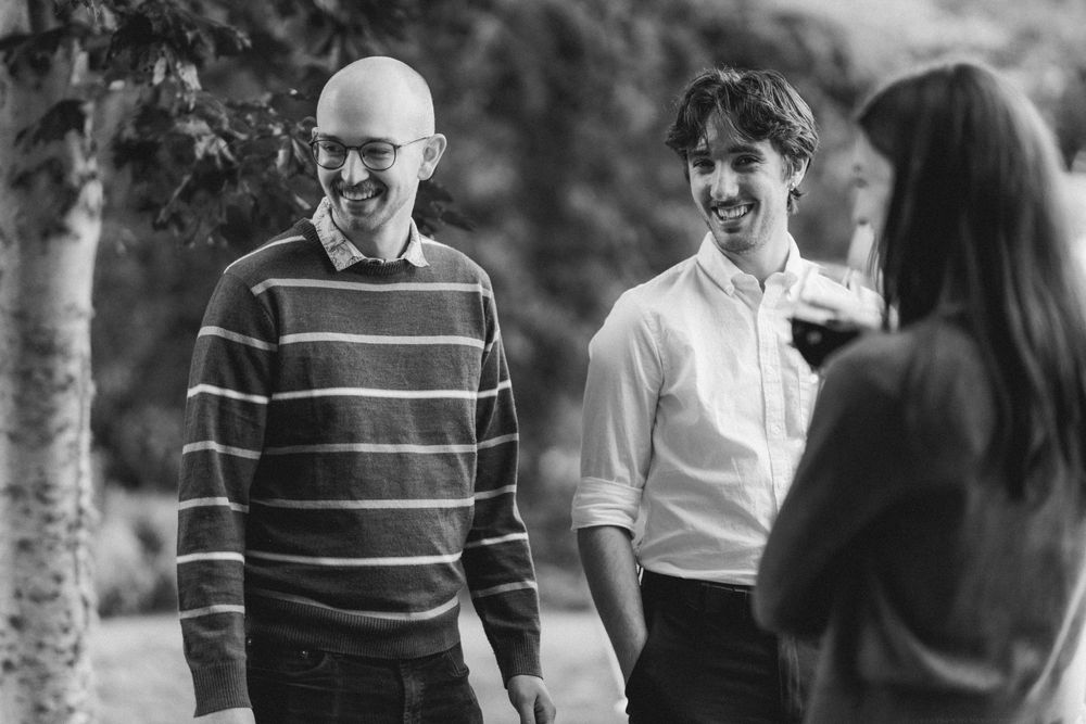 Black and white photo of three people engaged in conversation outdoors.