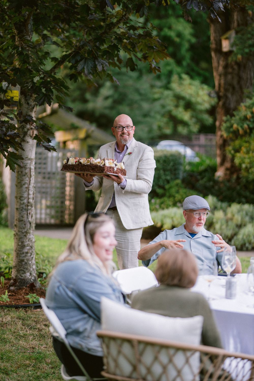People enjoying a casual outdoor gathering with table service under trees.