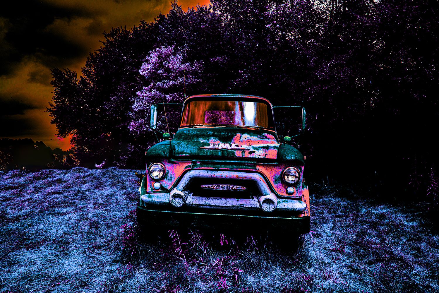 Vintage GMC truck illuminated at night with purple trees in the background.