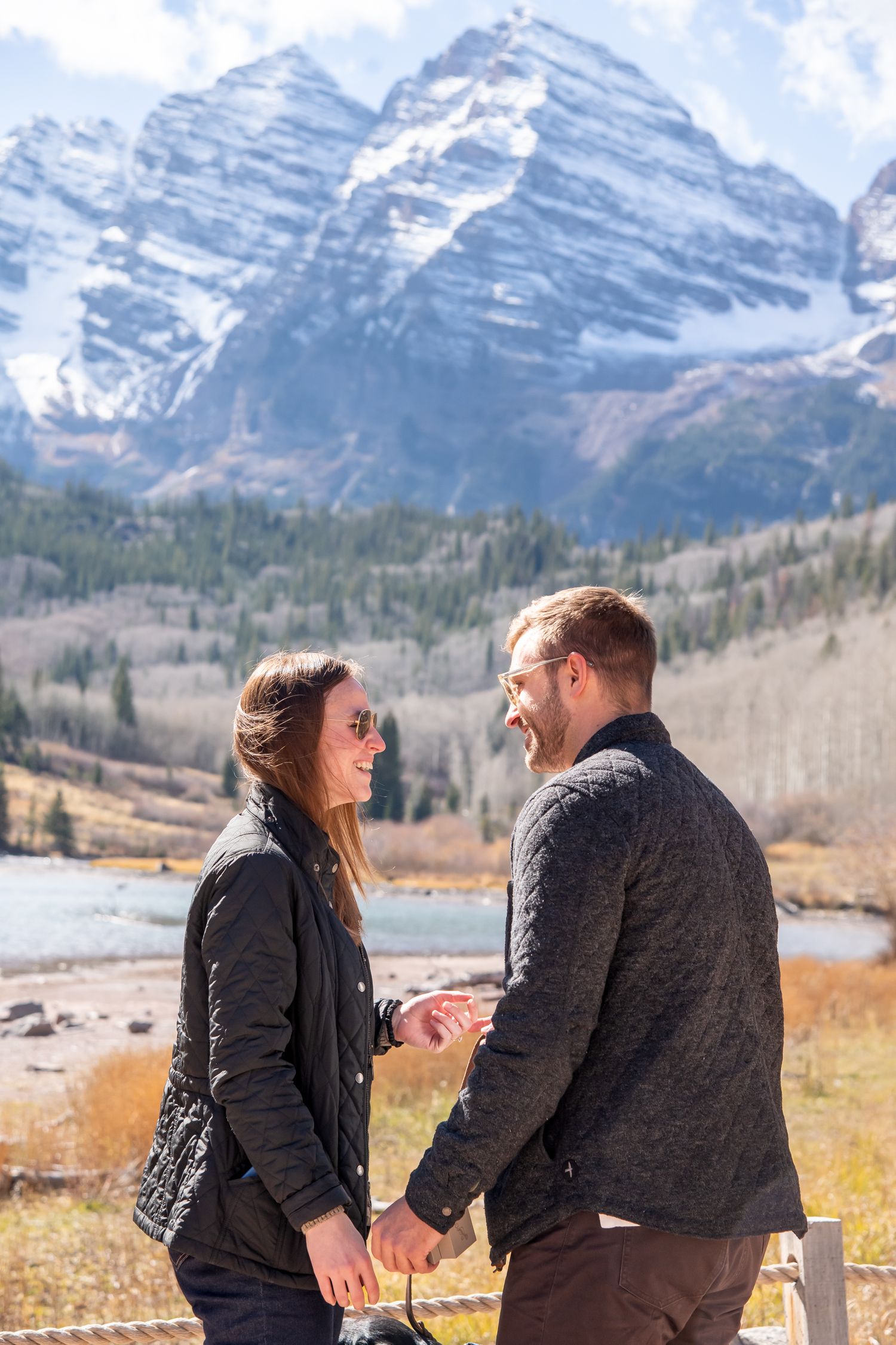 A couple shares a romantic moment in front of snow-capped mountains at The Maroon Bells after a proposal