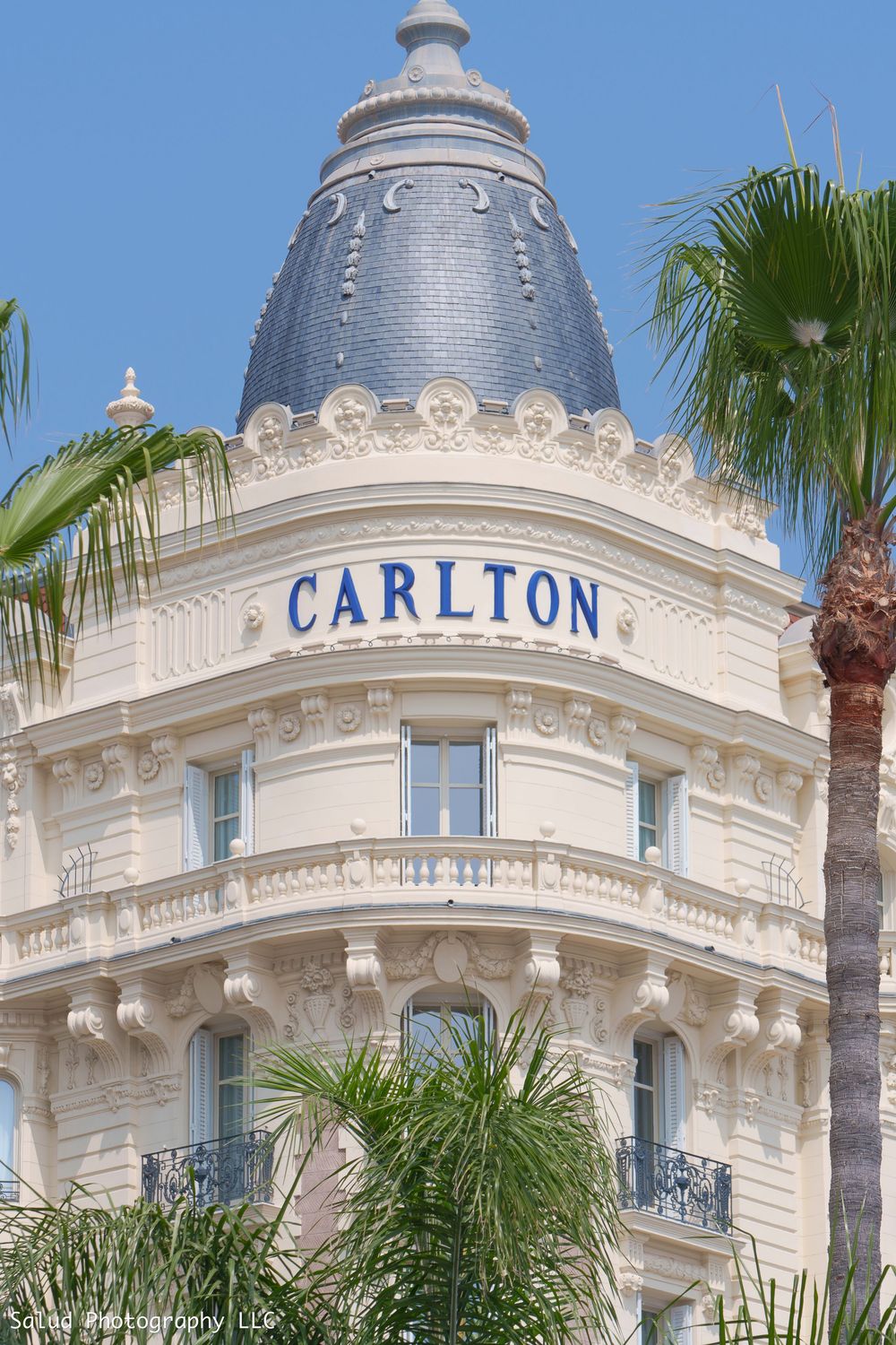 The ornate facade of the historic Carlton hotel features elegant French architecture with white stone and decorative details.