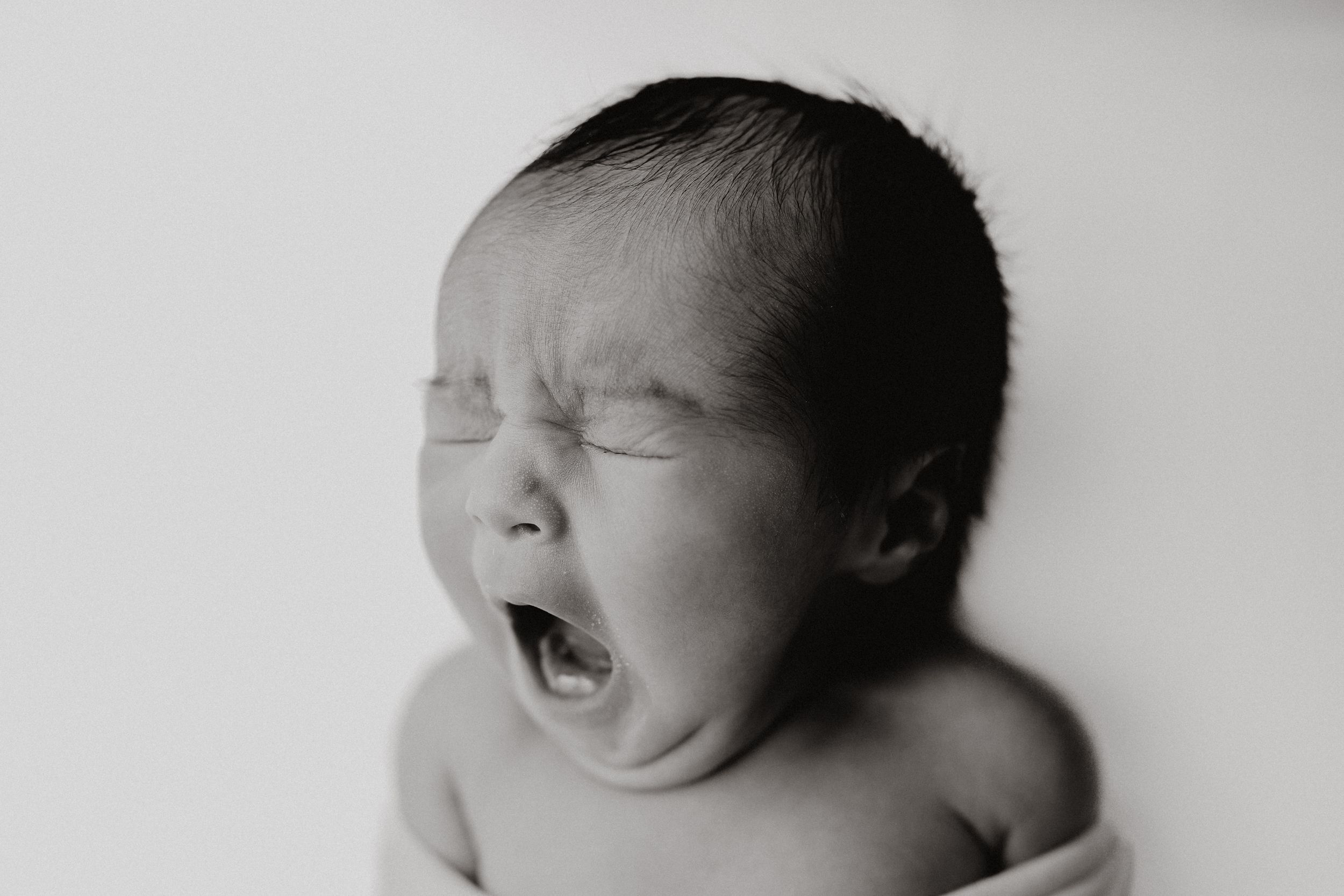 Black and white photo collage showing a sleeping baby in four different peaceful poses.