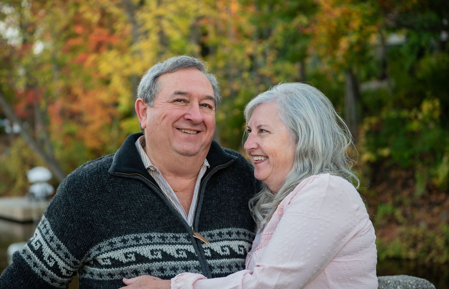 Couple in winter sweaters sharing romantic moments together in an autumn park setting with golden foliage.