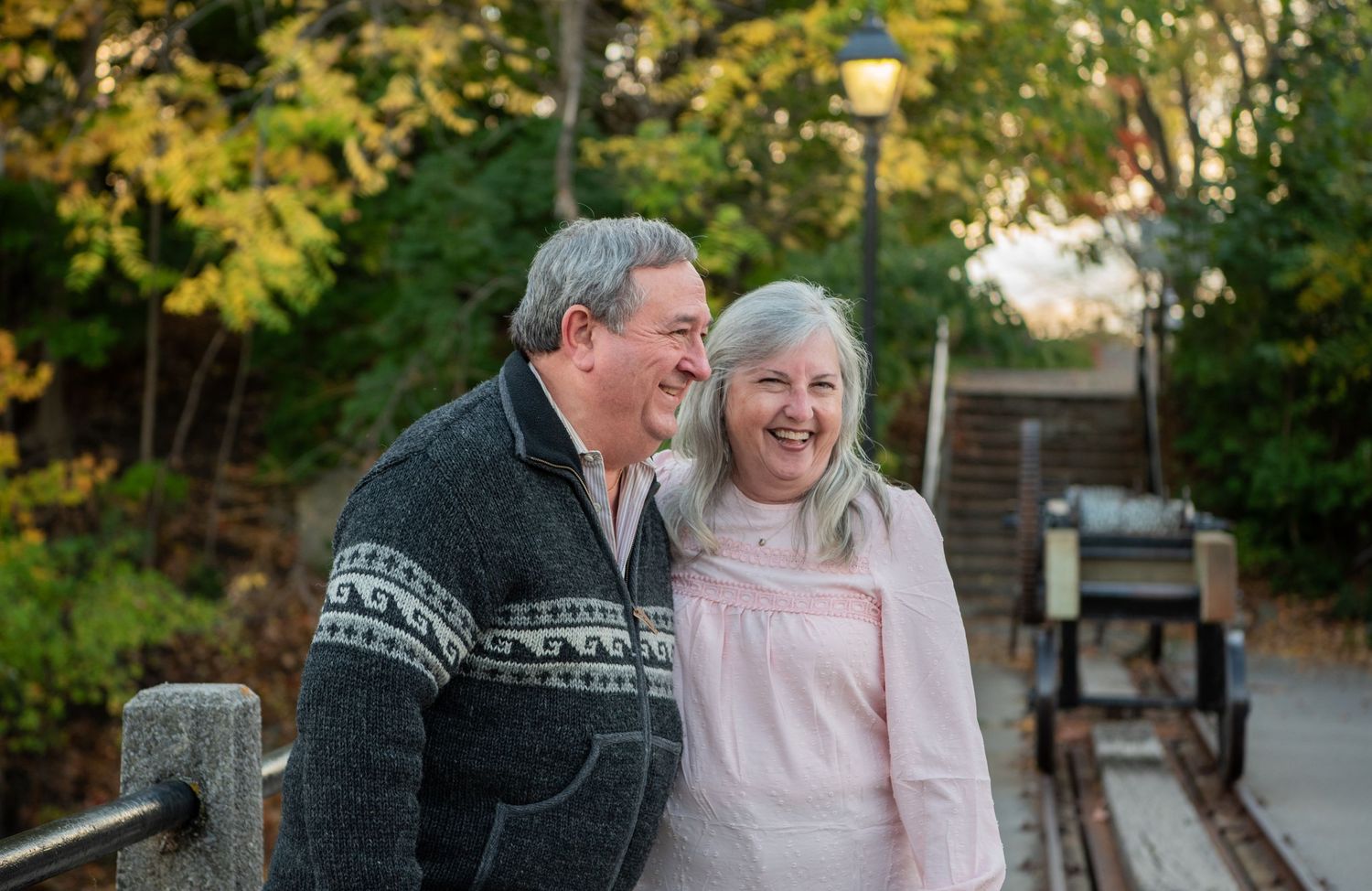 A couple shares joyful moments together outdoors in a garden setting during golden hour lighting.