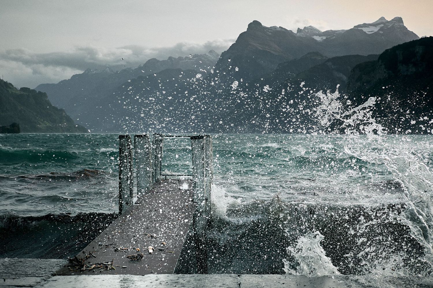 Ocean waves crash against rocky cliffs along a dramatic coastal shoreline as storm clouds gather overhead.
