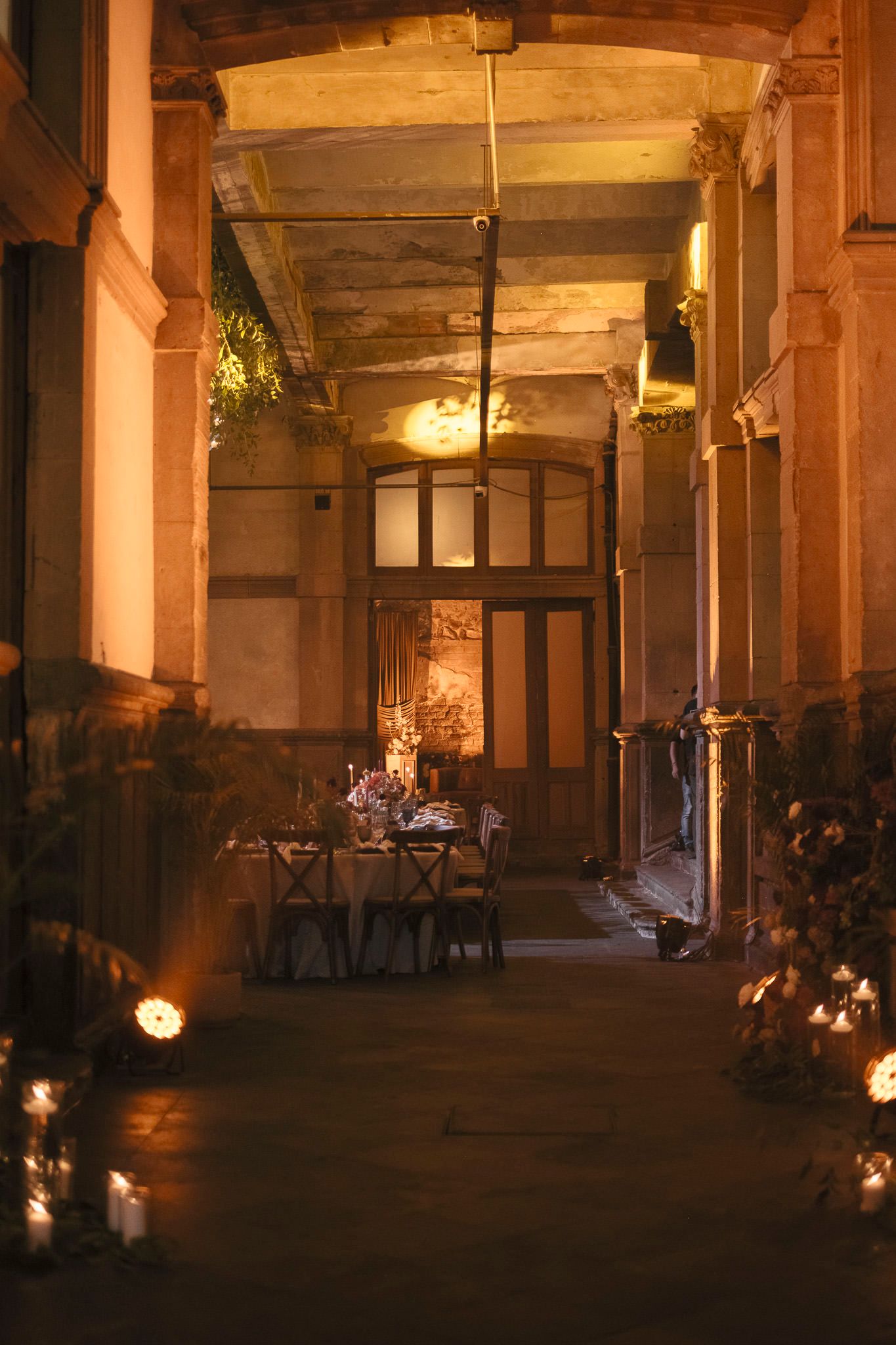 Dimly lit interior of historic building with stone columns and warm ambient lighting creating atmospheric shadows.
