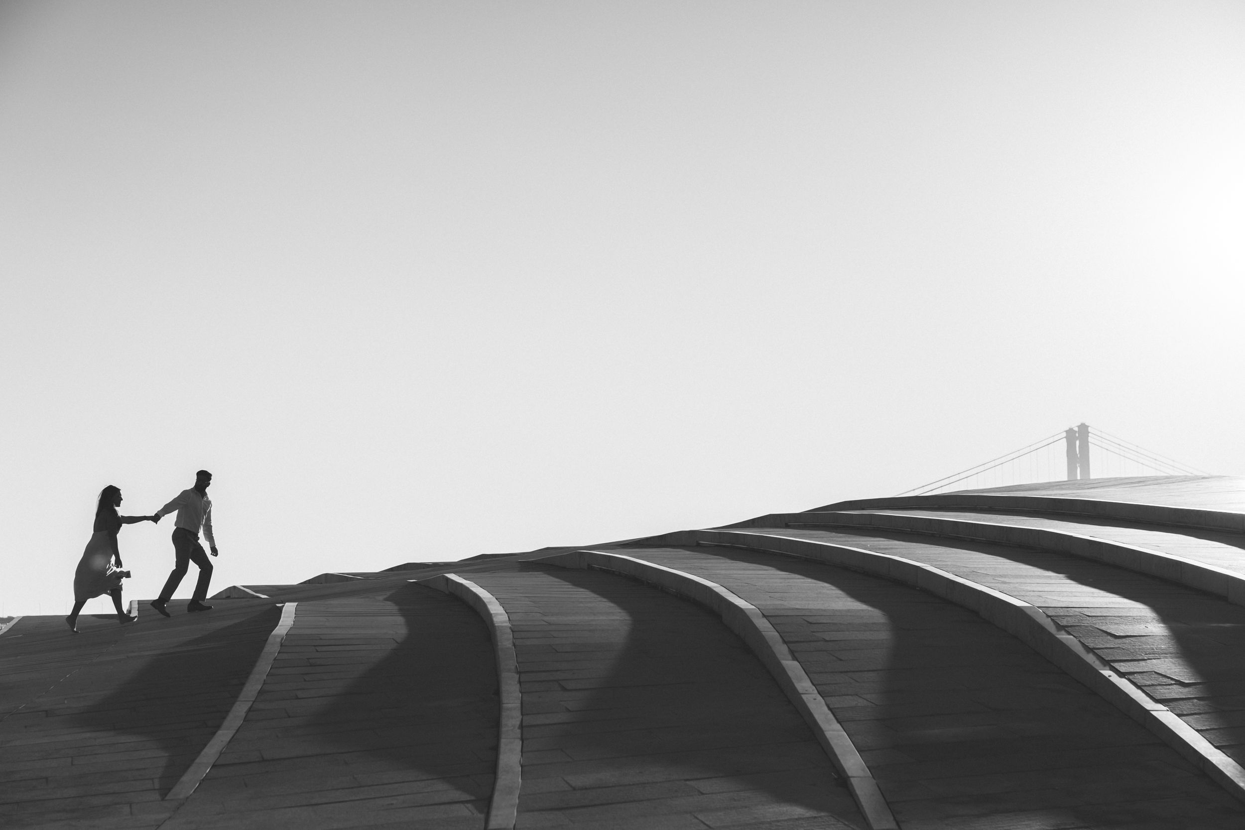 Cinematic black and white image of couple with the lisbin bridge in the background. captured by a portugal wedding photographer