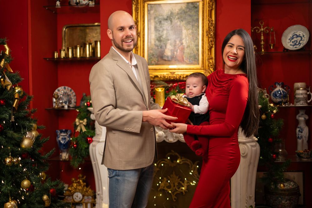 Familia con bebe de 1 año posando con un decorado festivo navideño