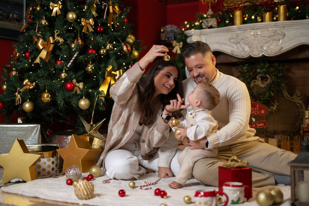 Una familia comparte tiernos momentos juntos frente a un árbol de Navidad decorado durante una sesión de fotos navideña.