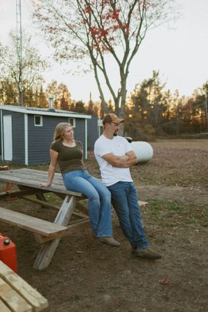 Couple relaxing on a picnic table in a backyard with autumn scenery.