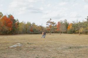 Wide landscape view of a couple in an open field during autumn.