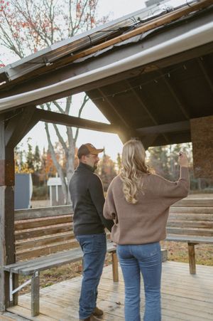 Couple standing together under a wooden shelter during sunset.