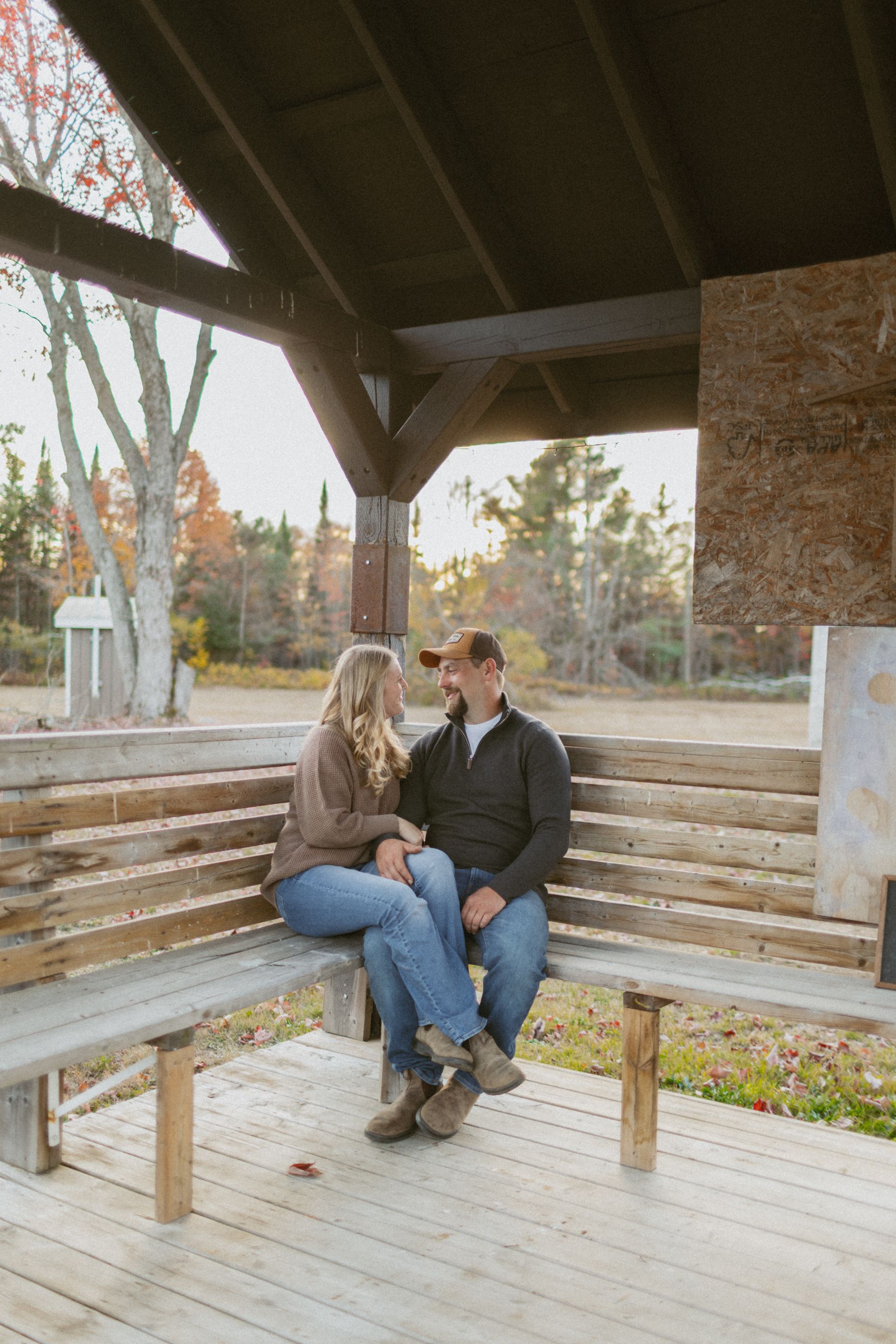 Couple sharing a moment on wooden benches under a covered pavilion.