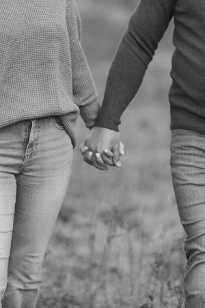 Close-up of two people holding hands while wearing casual fall attire.