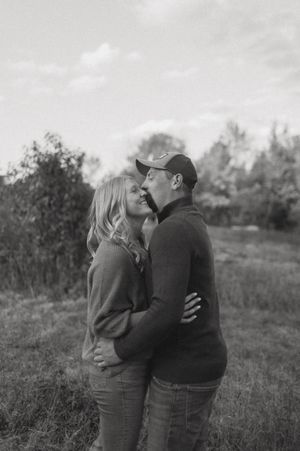 Black and white portrait of a couple sharing a tender moment in a natural setting.