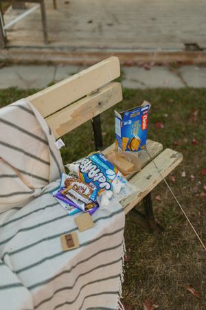 Snacks and treats arranged on a wooden bench with a striped blanket.