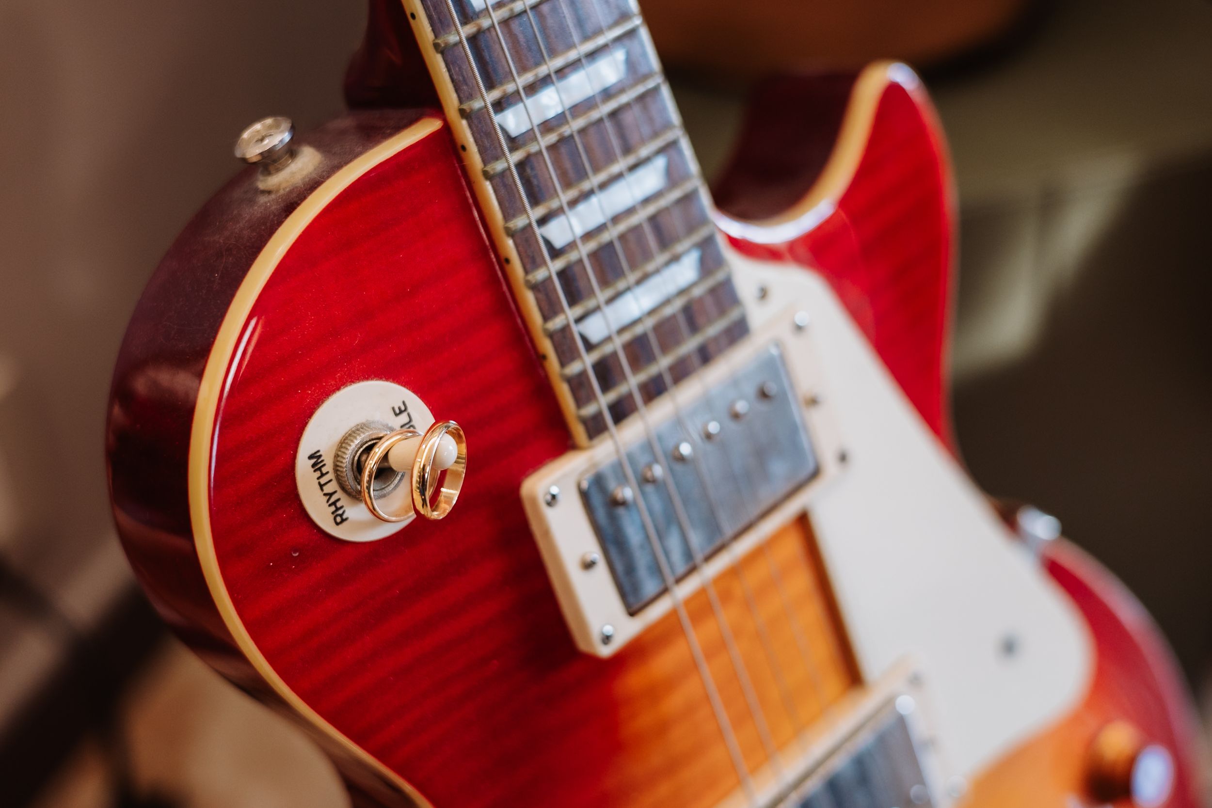Close-up detail of a red and sunburst electric guitar body and neck with chrome hardware.