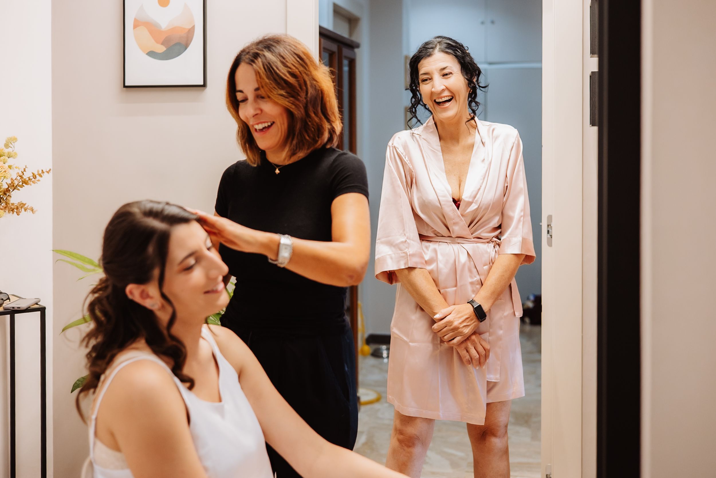 A group of people getting ready in a bridal suite with white robes and dresses for a wedding celebration.