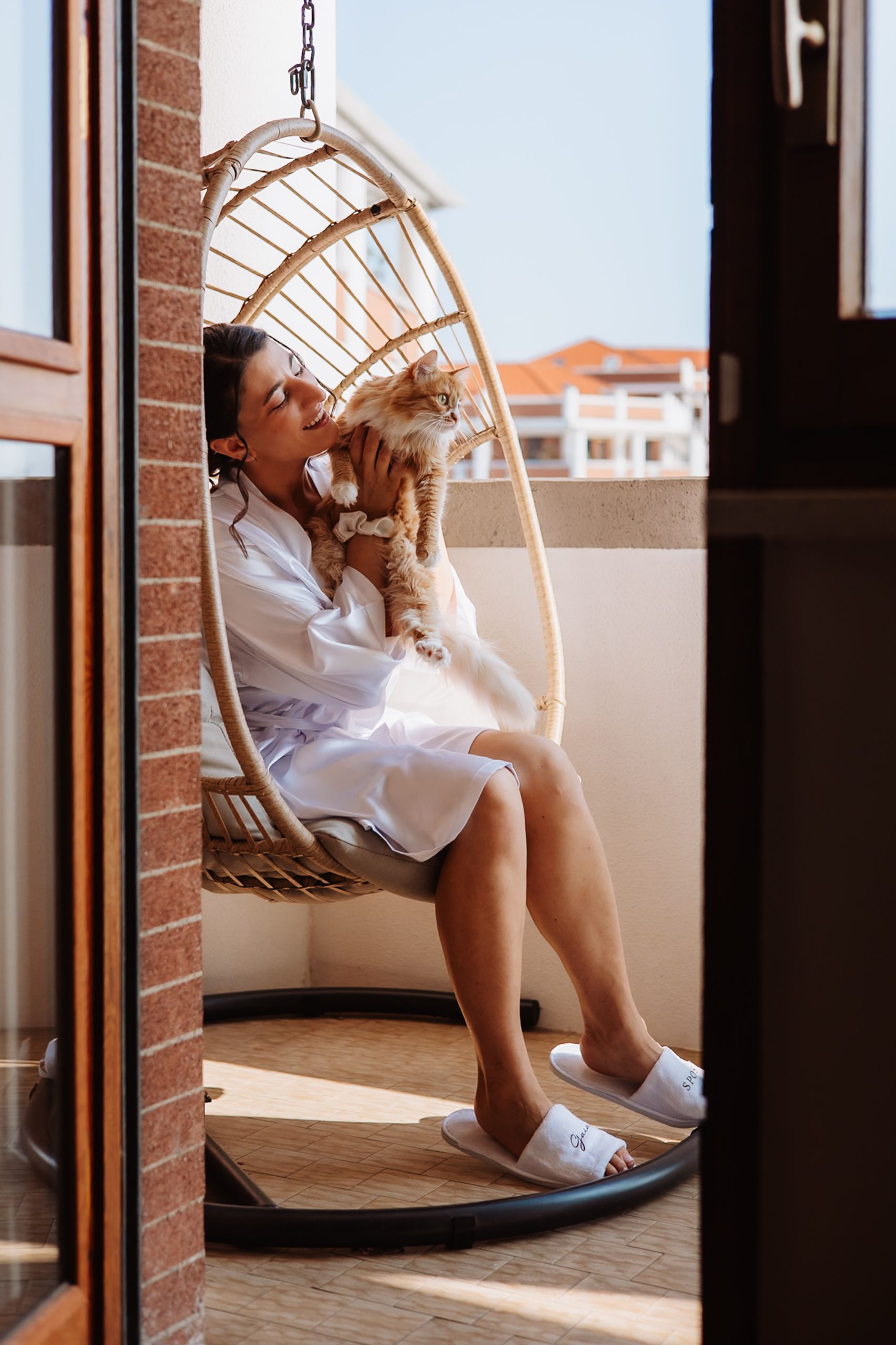 Person relaxing in a hanging swing chair by a window with warm sunlight streaming in.