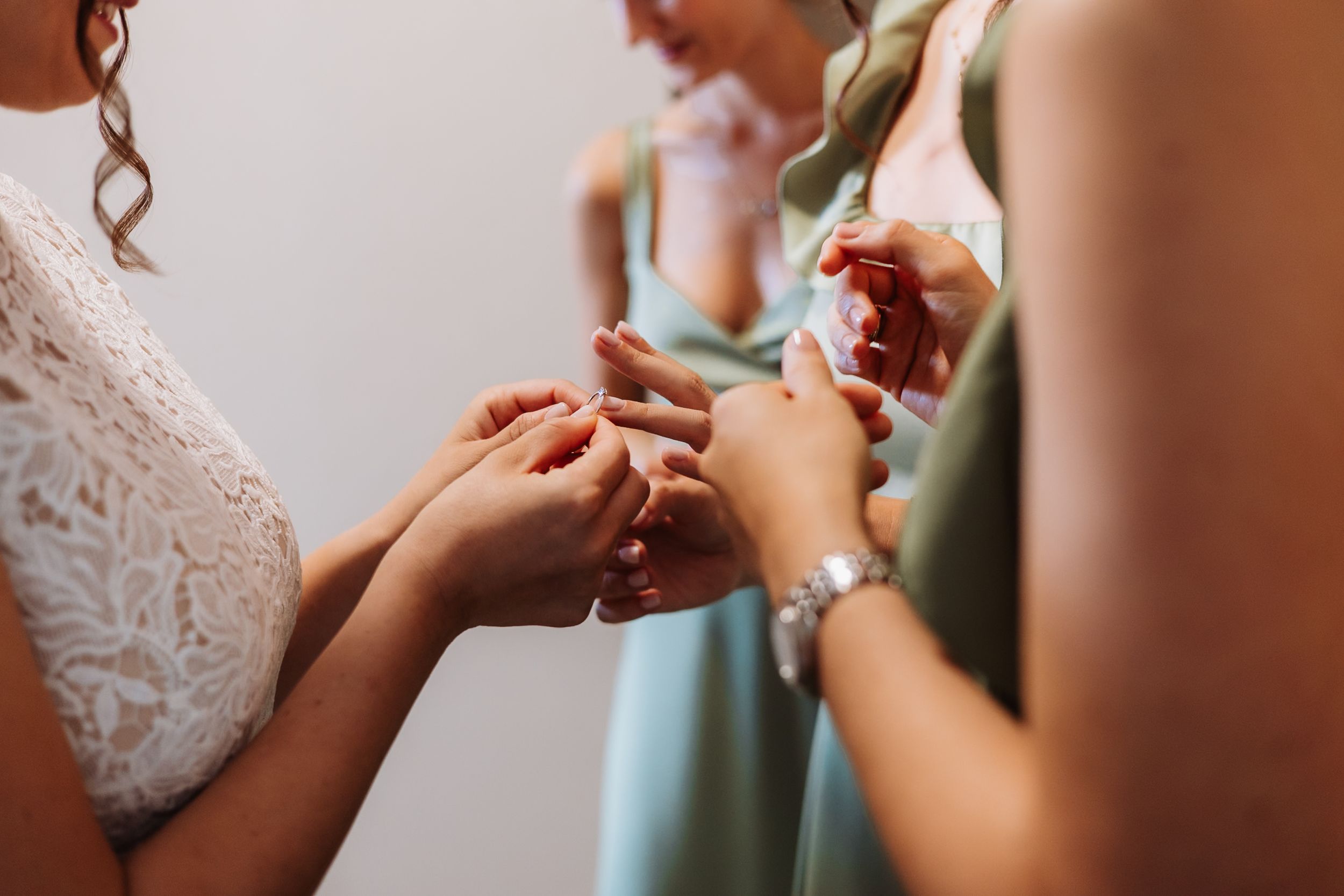 A sequence of photos showing someone putting on a delicate white lace wedding dress with intricate details.