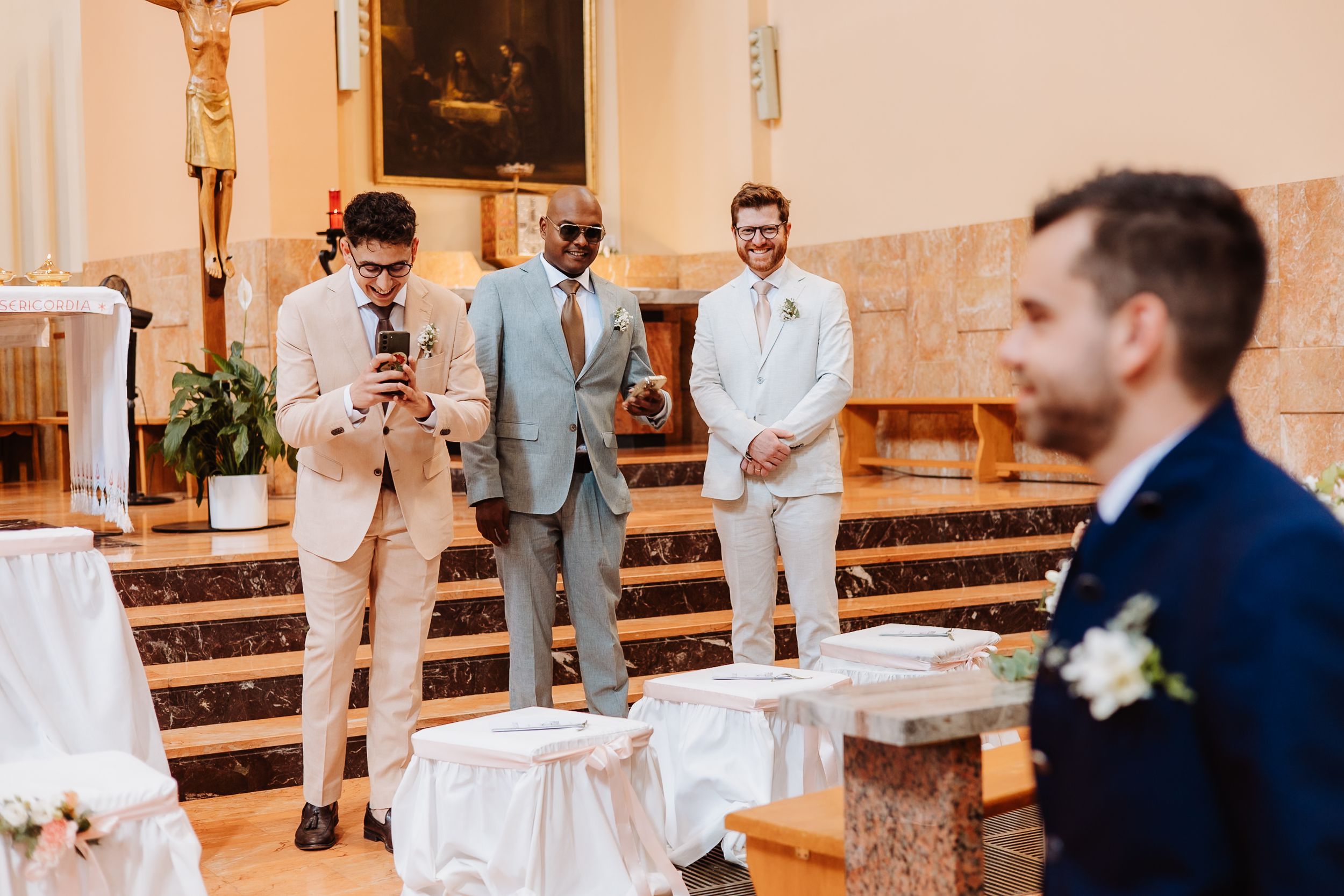 A wedding ceremony takes place in a traditional church with bridesmaids and groomsmen standing at the altar.