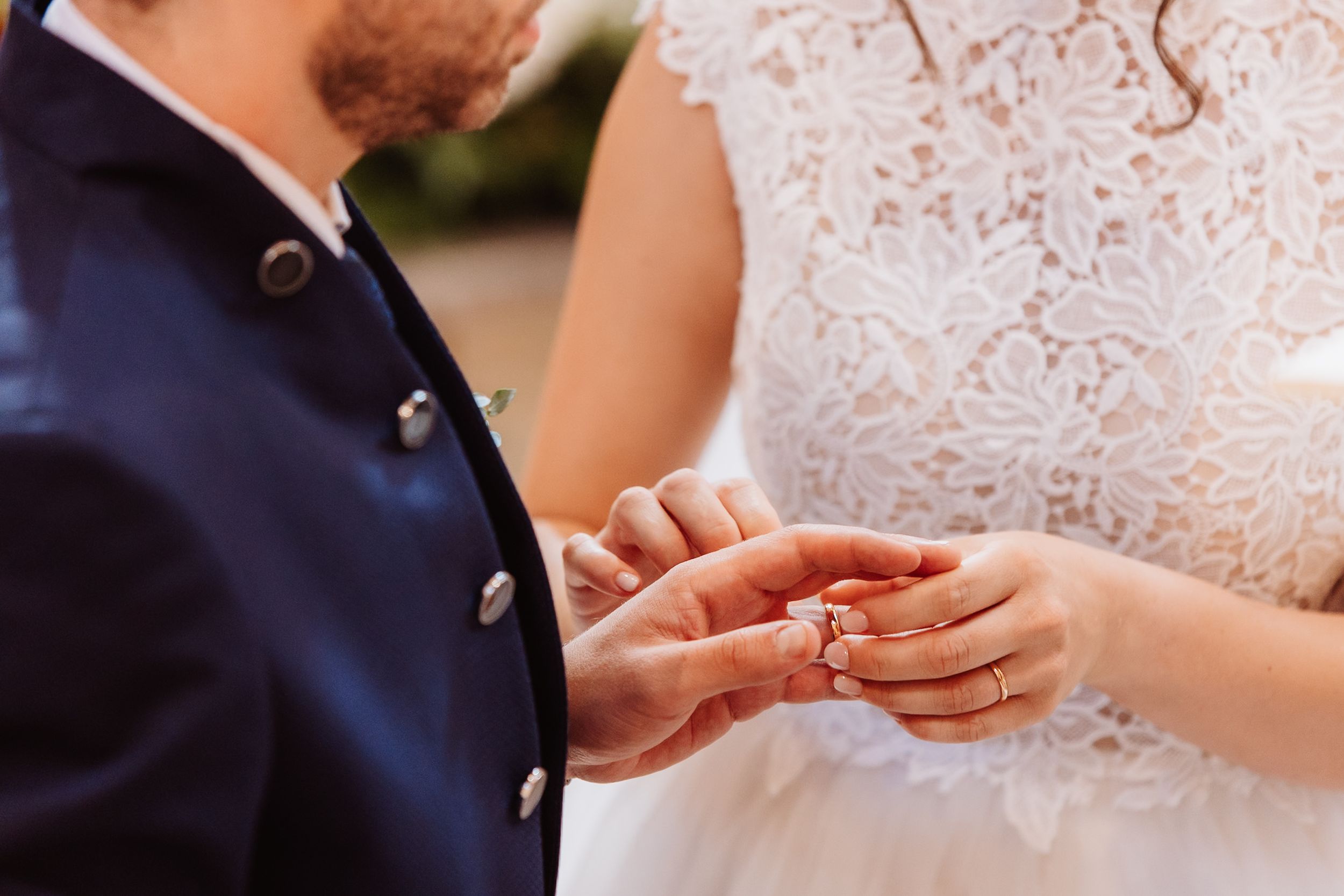 Close-up view of wedding rings being exchanged during a traditional ceremony.