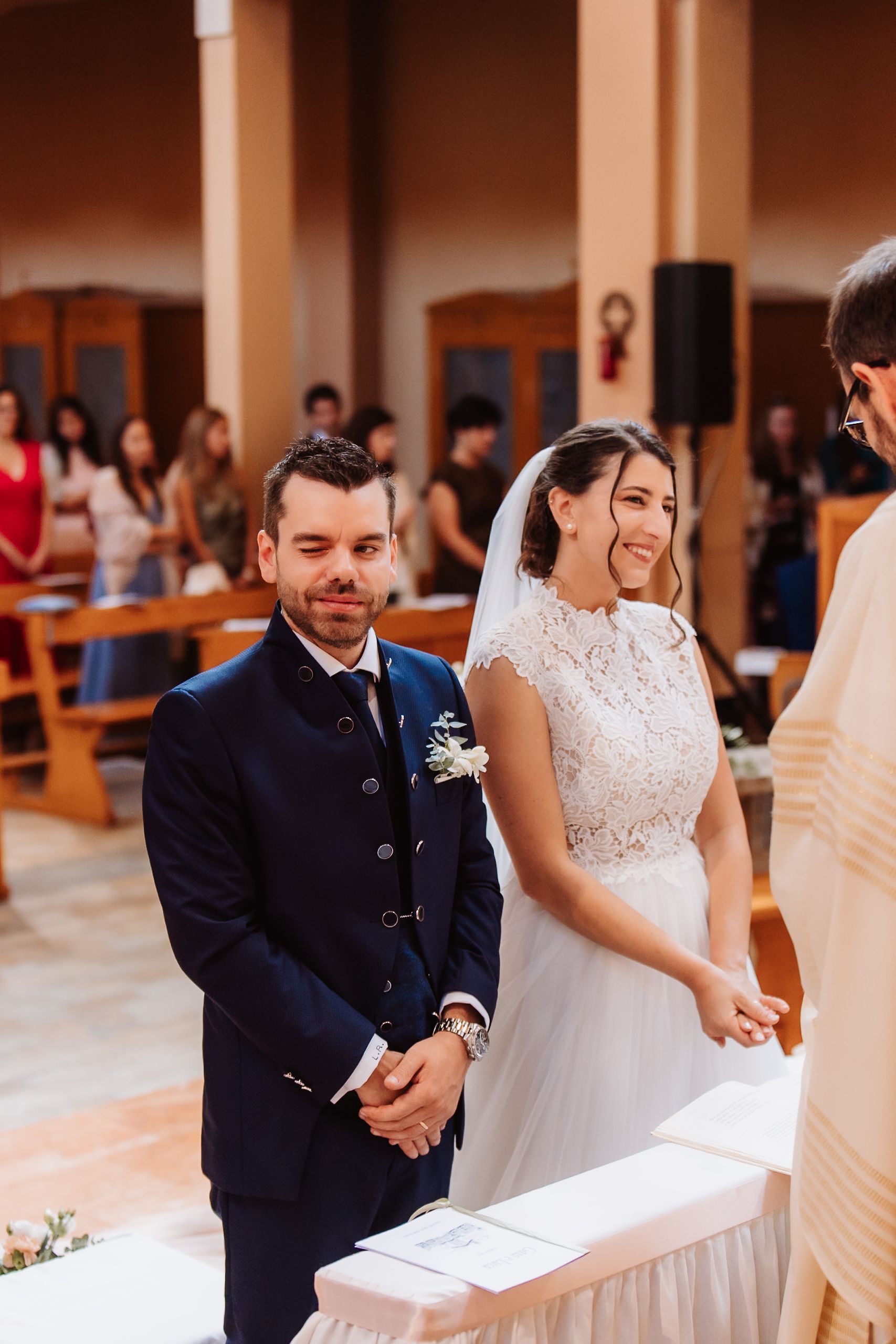 Joyful wedding ceremony with couple and guests gathered in an elegant indoor venue with warm lighting and decorative details.