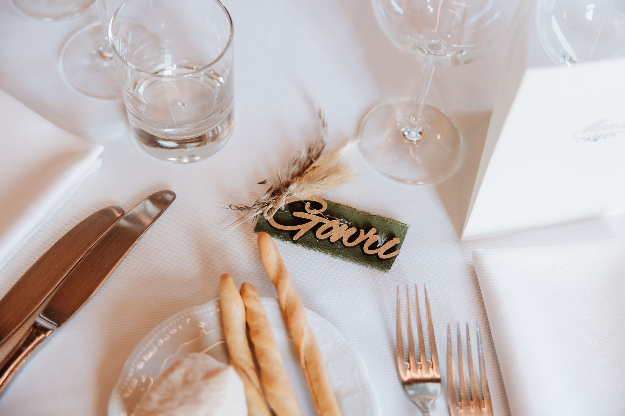 Elegant place settings with wine glasses and silverware on a white tablecloth at a formal event.