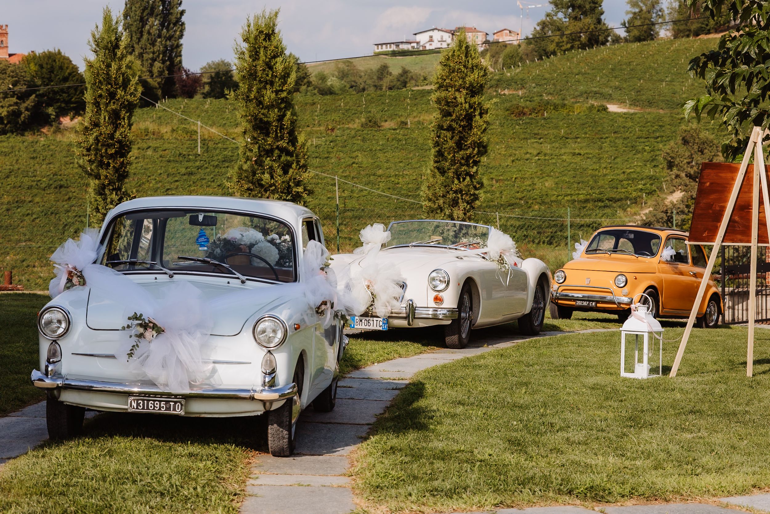 A collection of vintage cars parked on grassy terrain at a classic car meetup on a sunny day.