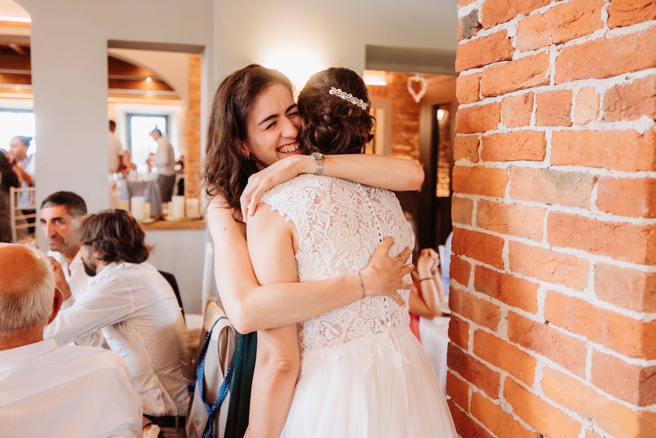 People dancing and celebrating at a rustic brick-walled venue during a joyful wedding reception.