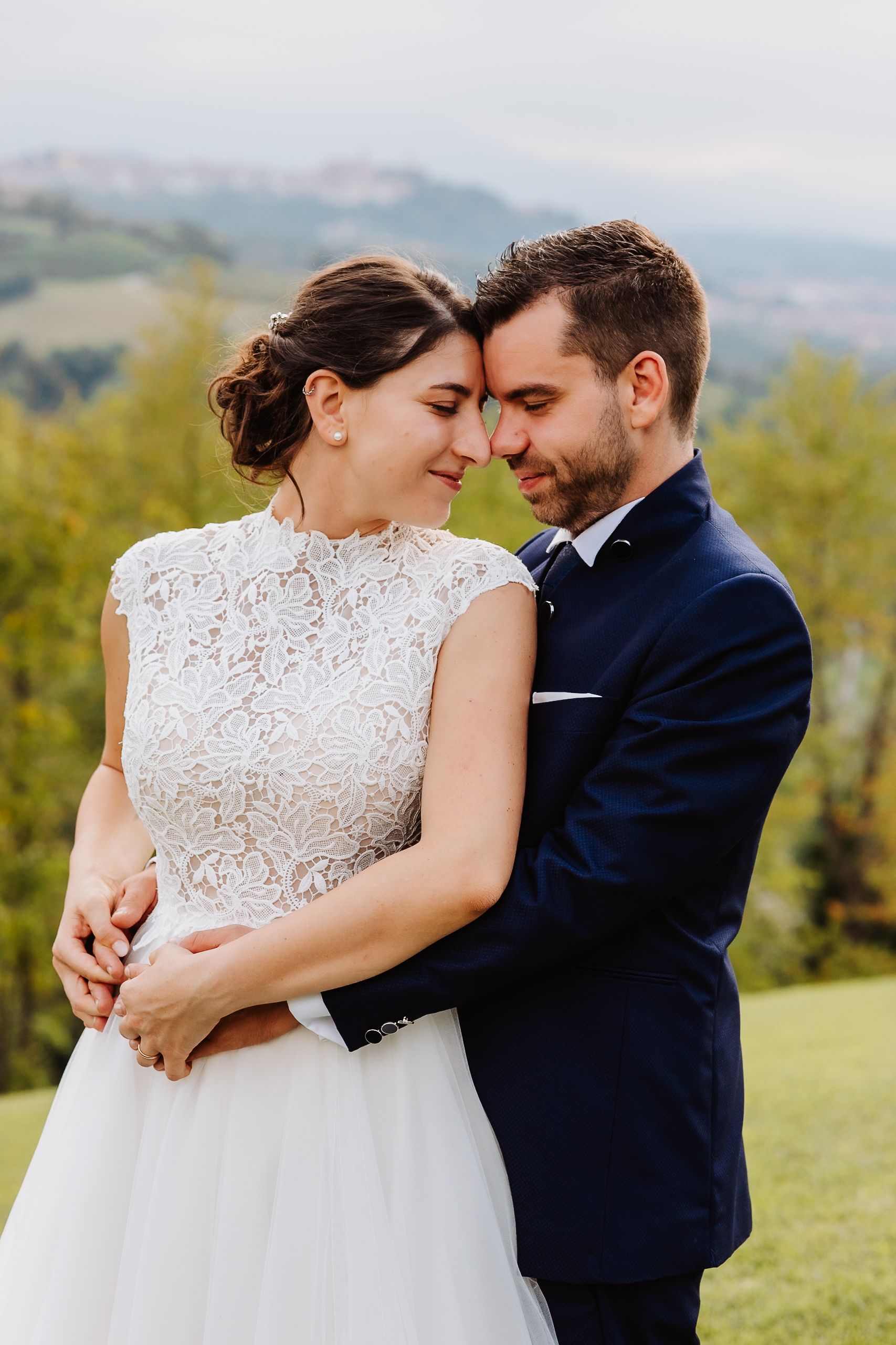 Romantic outdoor wedding couple embracing in a scenic mountain landscape with natural lighting.