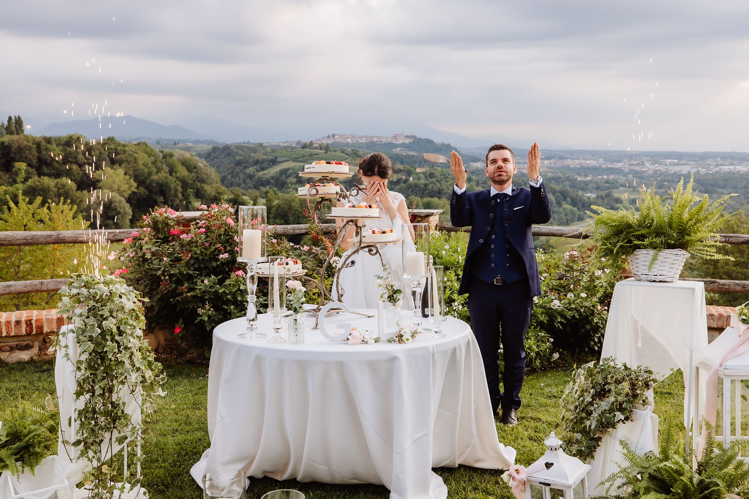 A scenic outdoor wedding reception setup with white tables and floral arrangements overlooking a mountain landscape.