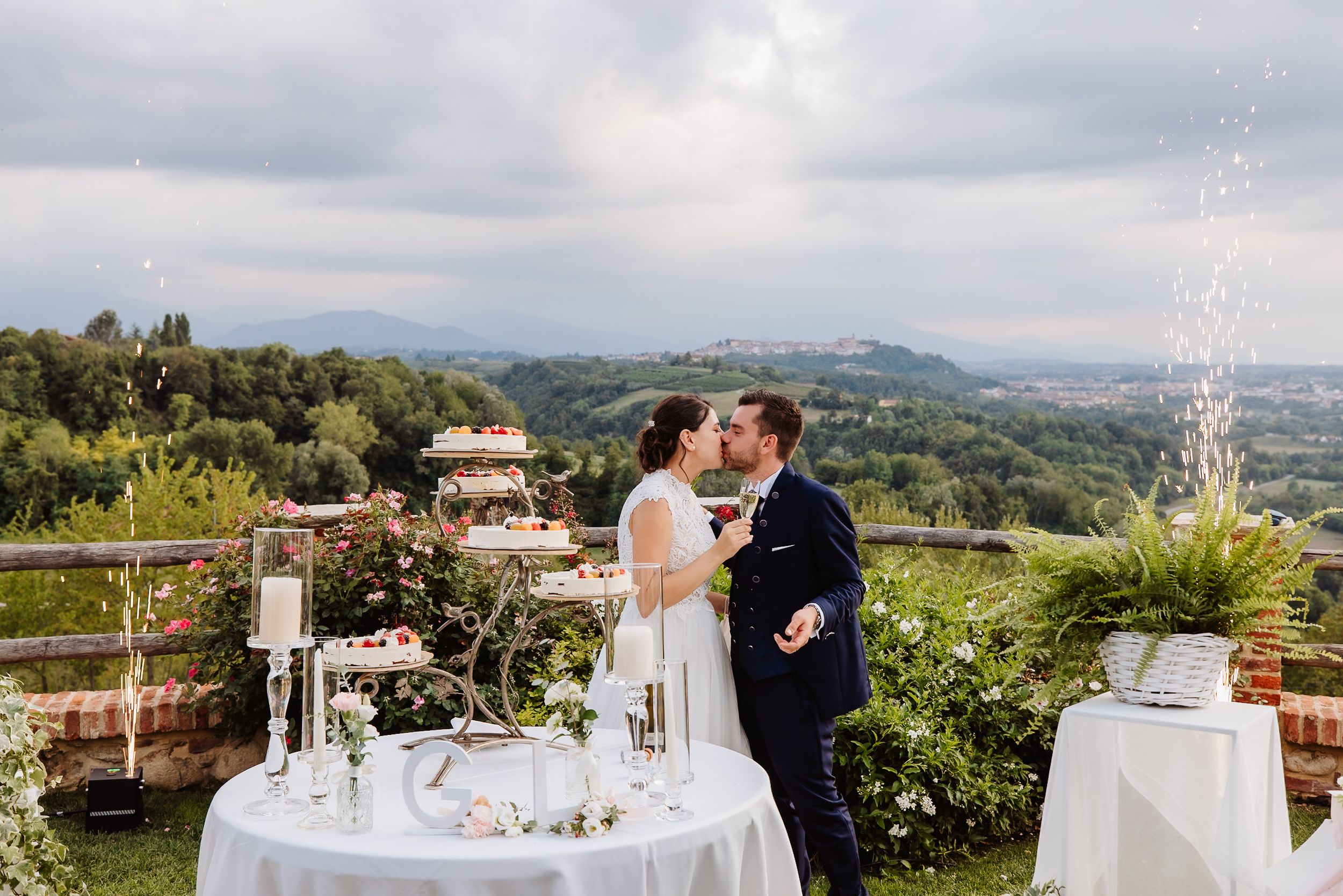 Elegant outdoor wedding reception setup overlooking a scenic Tuscan countryside villa and gardens.
