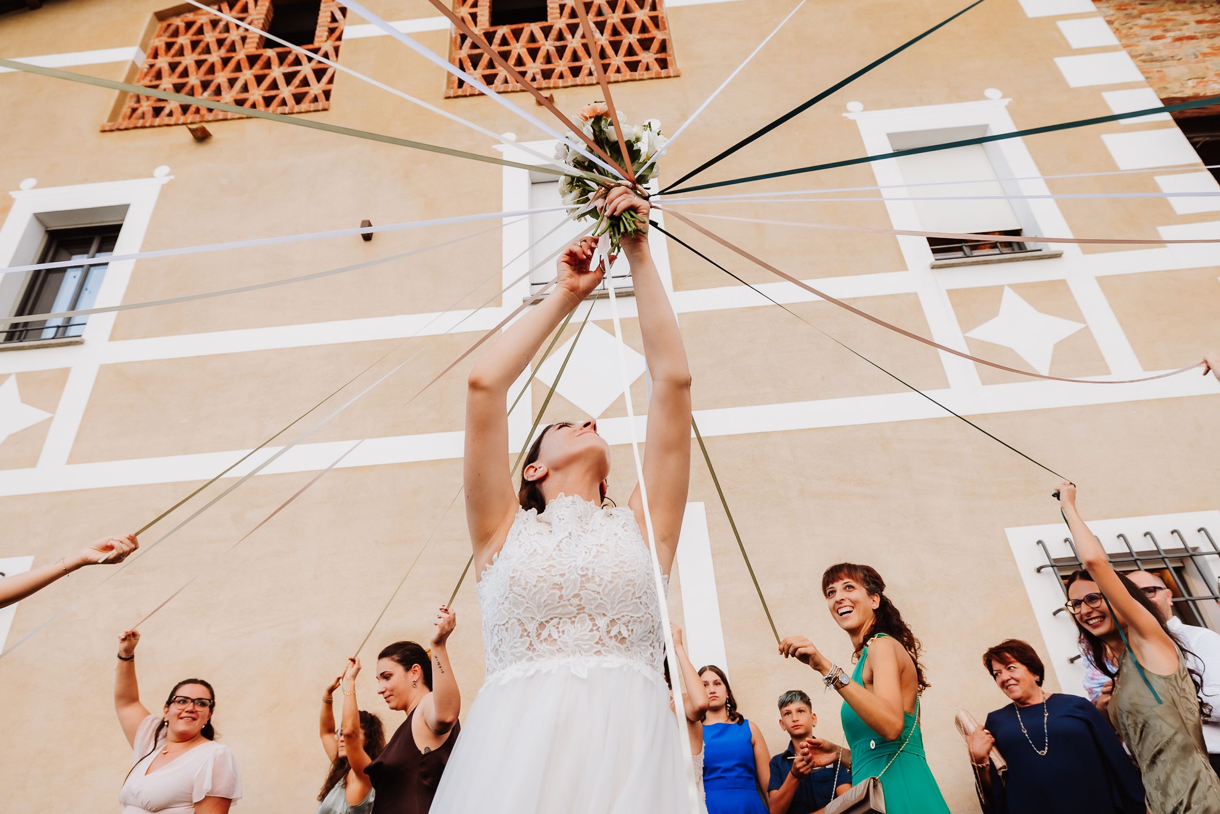 A group of people dancing and celebrating with raised arms in a white tent decorated for a wedding reception.